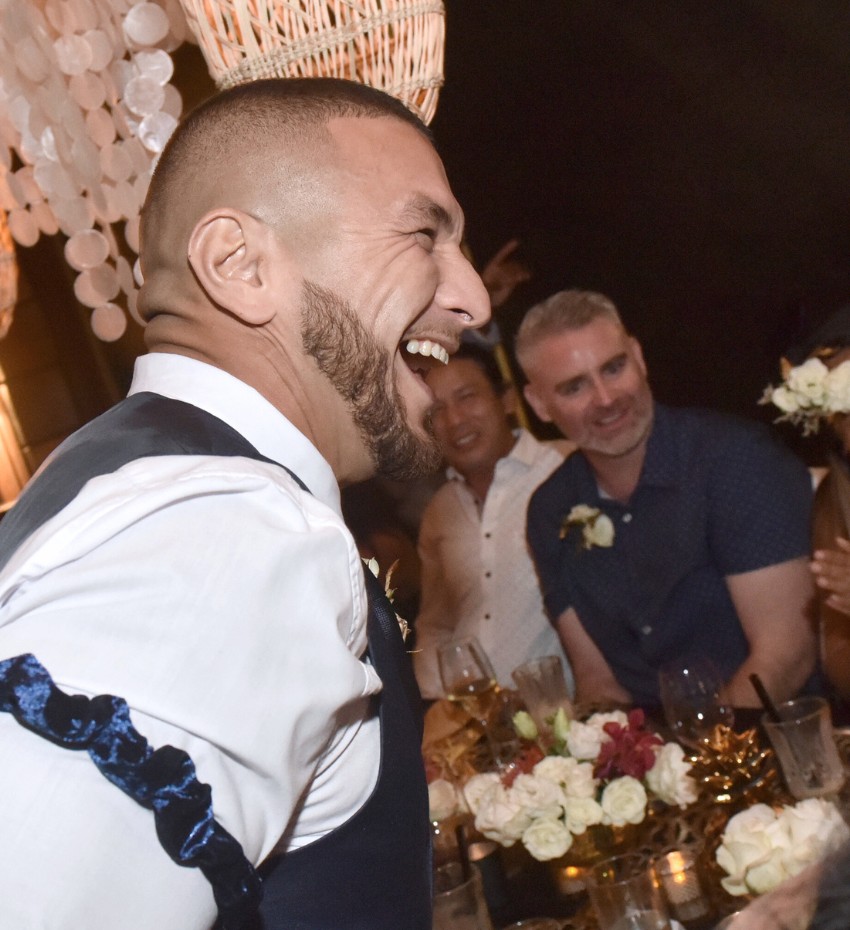 A man joyfully laughs with friends, celebrating together at a wedding.