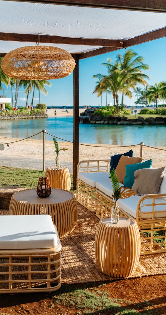 A beachside lounge featuring rattan furniture and a stunning view of the ocean.