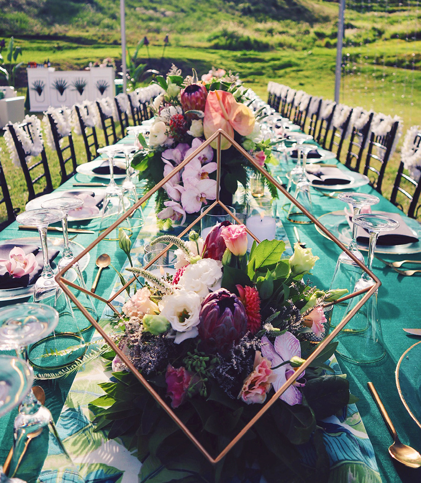 A long table covered with a green and gold tablecloth, adorned with beautiful flowers.